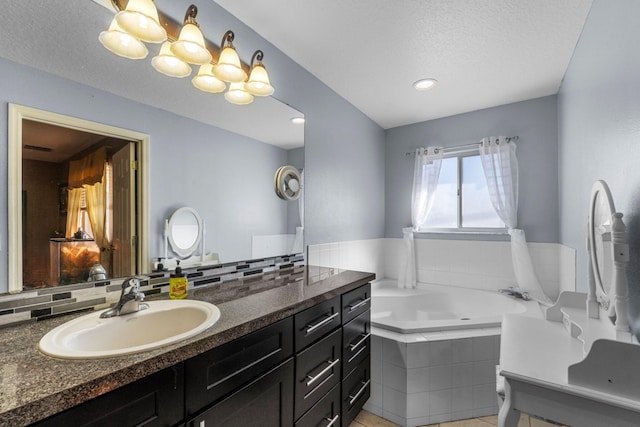 bathroom with a textured ceiling, vanity, decorative backsplash, and a bath