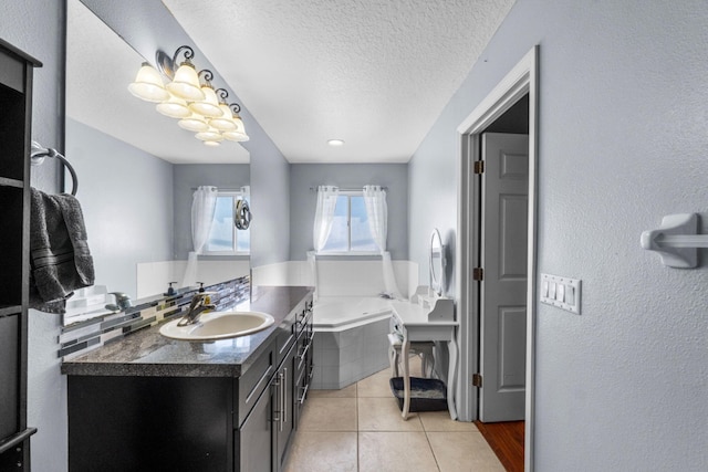 bathroom with a textured ceiling, tile patterned flooring, vanity, and a bath