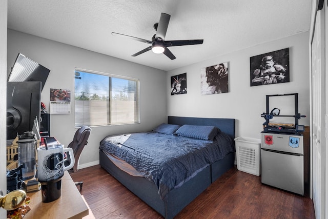 bedroom featuring freestanding refrigerator, ceiling fan, a textured ceiling, wood finished floors, and baseboards