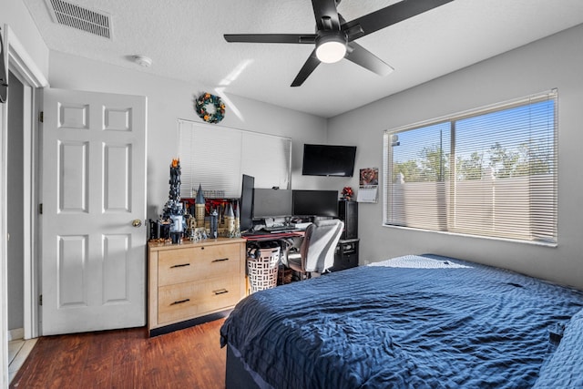 bedroom featuring a ceiling fan, a textured ceiling, visible vents, and wood finished floors