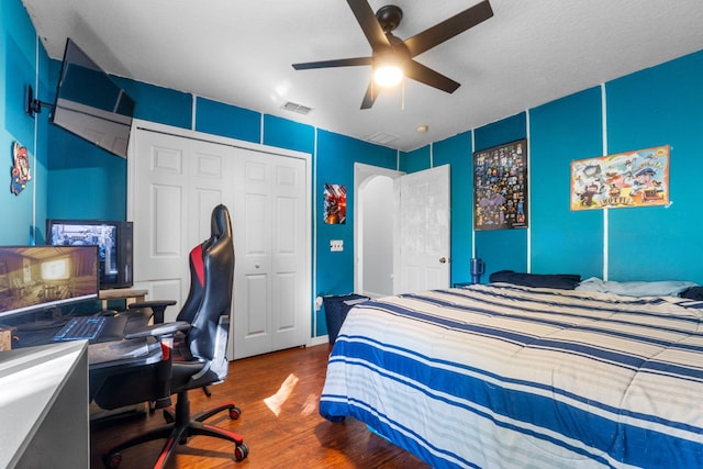 bedroom with a closet, wood finished floors, visible vents, and a ceiling fan