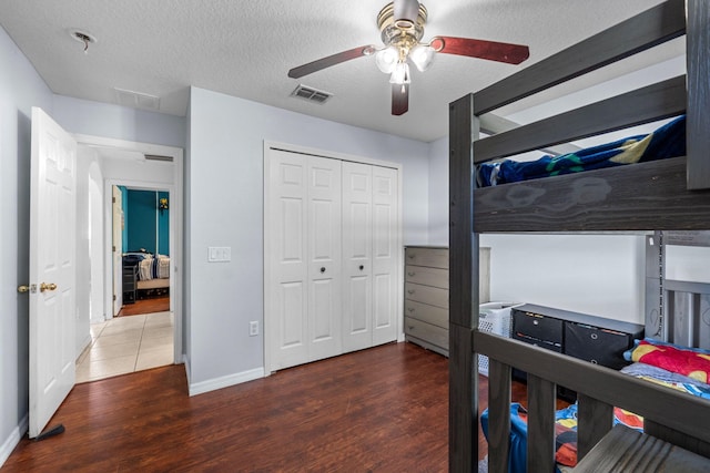 bedroom featuring a closet, a textured ceiling, visible vents, and wood finished floors