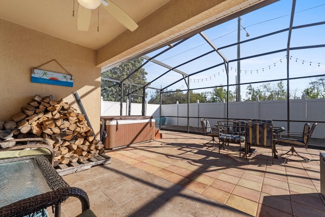 view of patio with a lanai, a hot tub, fence, and a ceiling fan