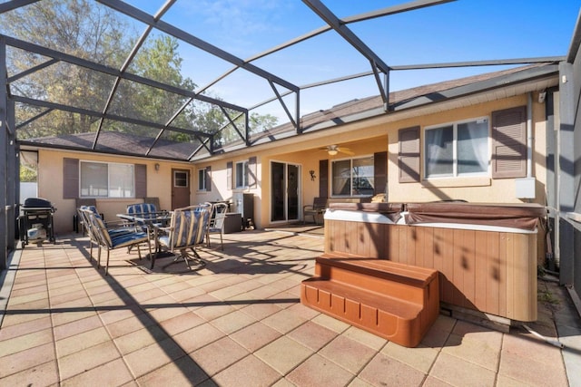 back of property with a lanai, a patio area, a hot tub, and stucco siding