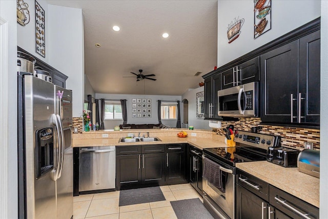 kitchen with kitchen peninsula, vaulted ceiling, appliances with stainless steel finishes, ceiling fan, and sink