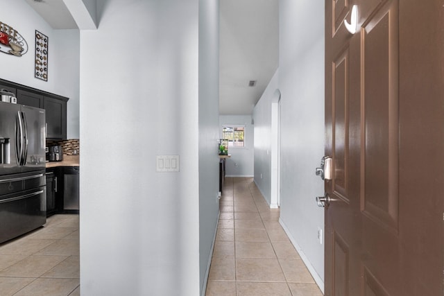 corridor with baseboards, arched walkways, and light tile patterned flooring