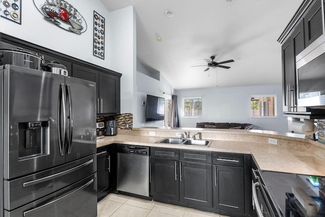 kitchen featuring stainless steel appliances, dark cabinetry, a sink, and light countertops