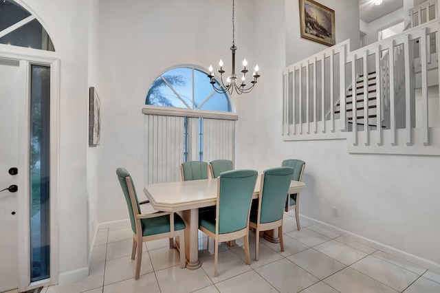 dining area featuring a towering ceiling, light tile patterned floors, and a notable chandelier