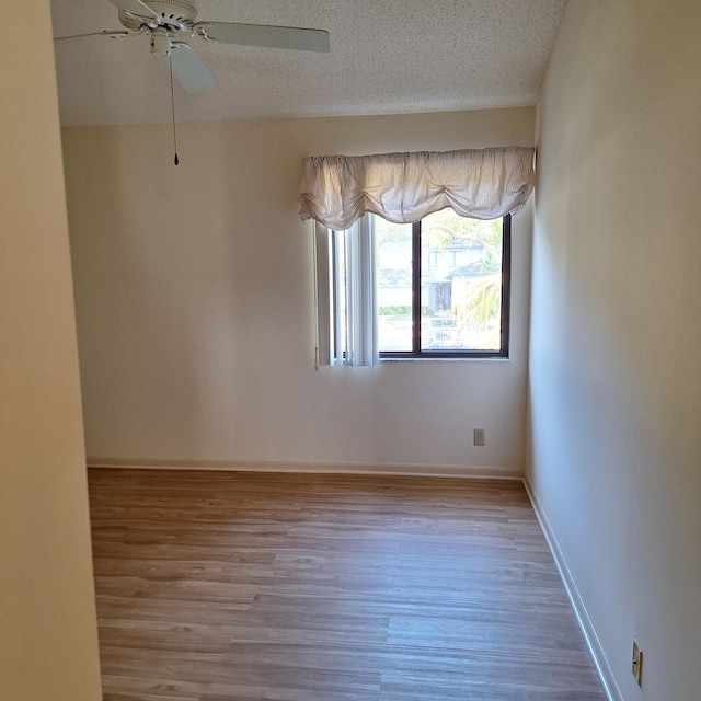 empty room with a textured ceiling, ceiling fan, and light hardwood / wood-style floors