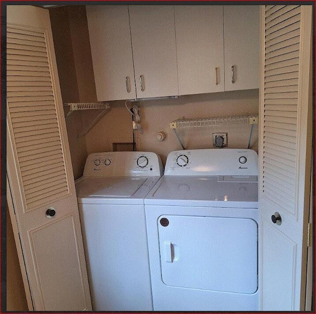 laundry area featuring separate washer and dryer and cabinets