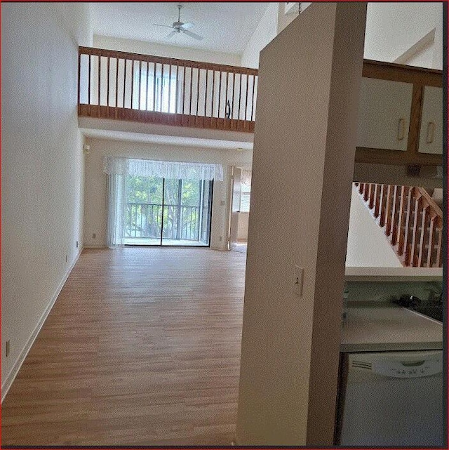 unfurnished living room with a towering ceiling, ceiling fan, and hardwood / wood-style floors