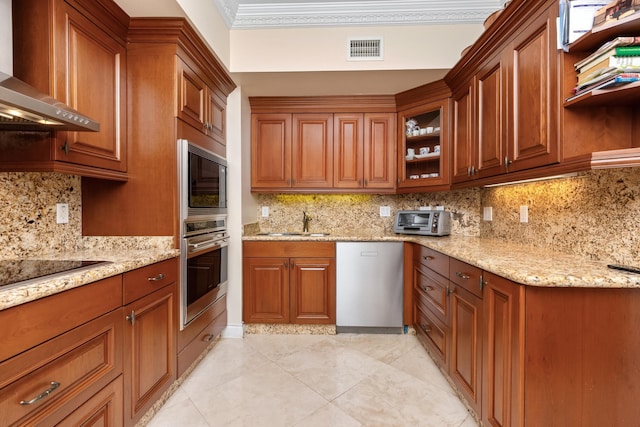 kitchen featuring sink, wall chimney range hood, light stone counters, and appliances with stainless steel finishes