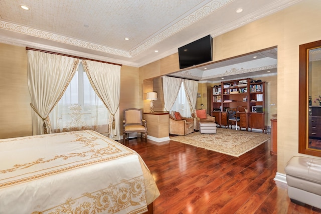 bedroom with wood-type flooring, ornamental molding, and a tray ceiling