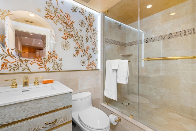 bathroom featuring toilet, vanity, tile walls, and a shower with shower door