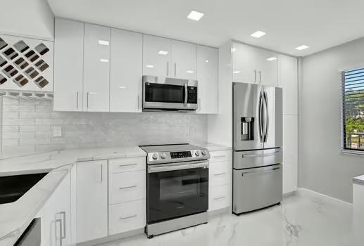 kitchen with stainless steel appliances, white cabinetry, backsplash, and modern cabinets