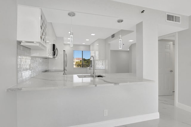 kitchen featuring white cabinetry, decorative light fixtures, kitchen peninsula, and light stone counters