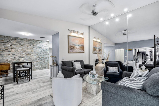 living room featuring ceiling fan, light hardwood / wood-style floors, and vaulted ceiling