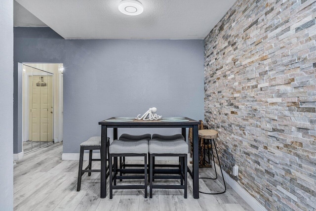 dining space with light hardwood / wood-style floors and a textured ceiling