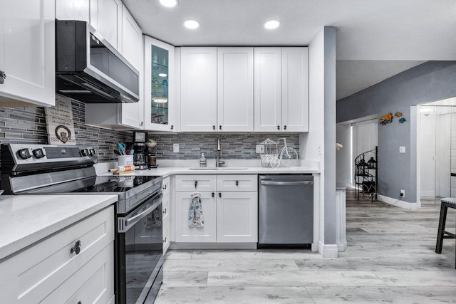 kitchen with sink, light wood-type flooring, white cabinetry, stainless steel appliances, and decorative backsplash