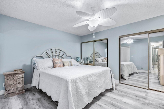 bedroom with light hardwood / wood-style floors, multiple closets, and a textured ceiling