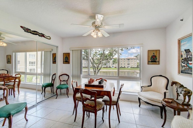 tiled dining room with a textured ceiling and ceiling fan