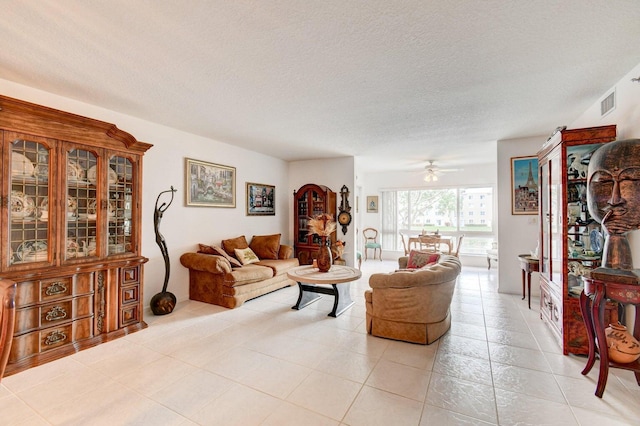 living room featuring a textured ceiling, light tile patterned flooring, and ceiling fan