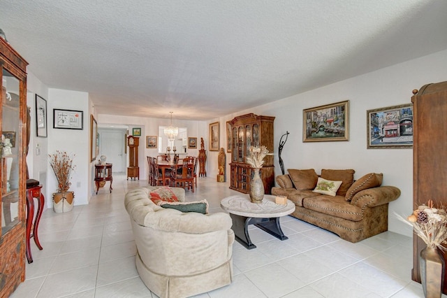 living room with a textured ceiling, an inviting chandelier, and light tile patterned floors