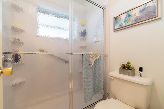 bathroom featuring toilet and a shower with shower door