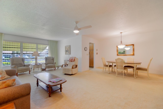 living room featuring ceiling fan, light carpet, and a textured ceiling