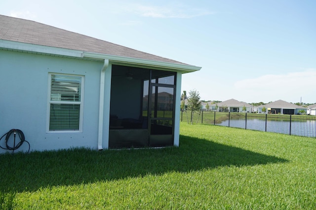 view of yard featuring a sunroom and a water view