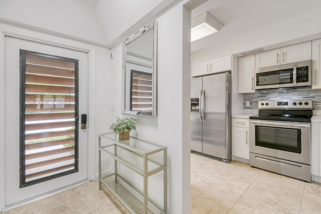 kitchen featuring light tile patterned floors, white cabinets, appliances with stainless steel finishes, and tasteful backsplash