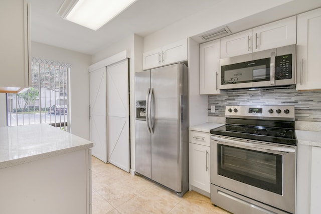 kitchen with white cabinets, light stone countertops, stainless steel appliances, and decorative backsplash