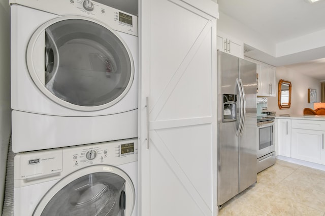 laundry area featuring light tile patterned floors and stacked washer / drying machine