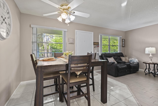 dining space with a wealth of natural light, a textured ceiling, ceiling fan, and light tile patterned floors