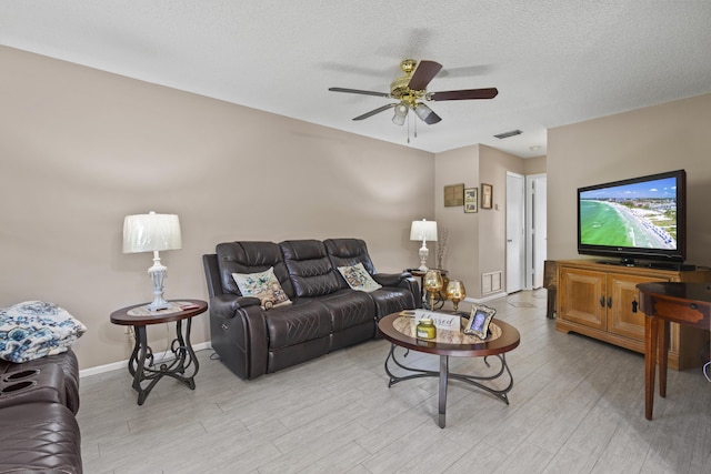 living room featuring ceiling fan, a textured ceiling, and light wood-type flooring