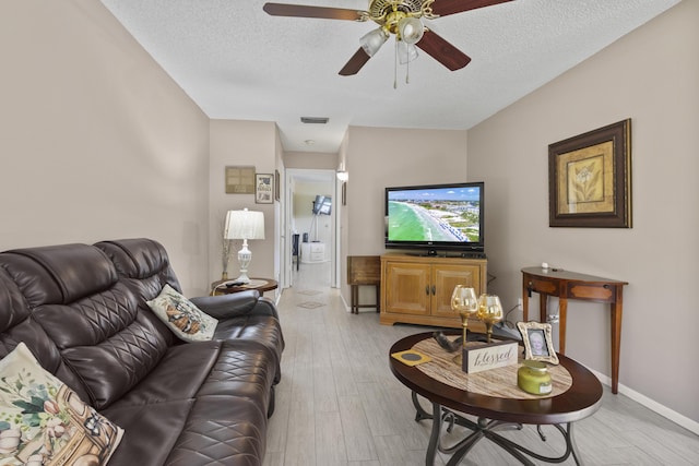 living room featuring ceiling fan, a textured ceiling, and light wood-type flooring