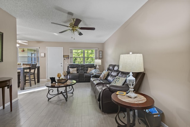 living room featuring hardwood / wood-style flooring, ceiling fan, and a textured ceiling