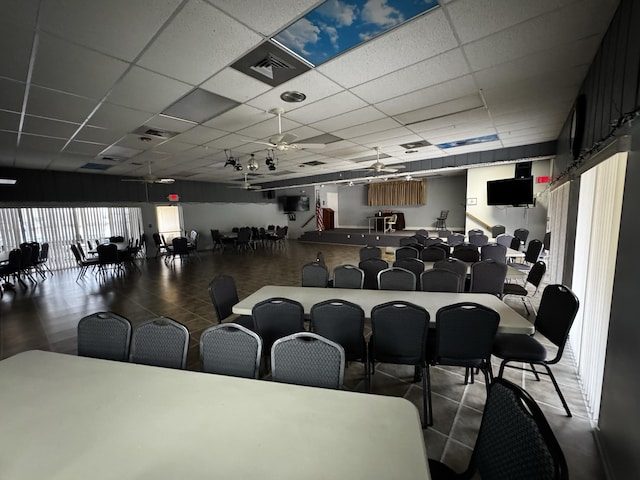 cinema room with ceiling fan and a drop ceiling