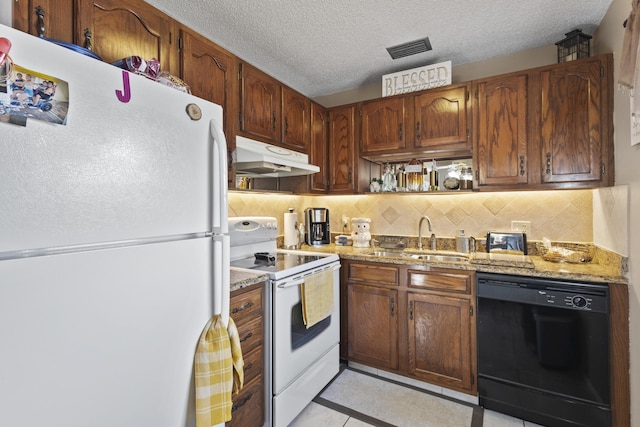 kitchen featuring sink, white appliances, light tile patterned floors, light stone countertops, and a textured ceiling