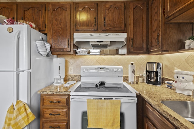 kitchen featuring light stone countertops, white appliances, range hood, and decorative backsplash