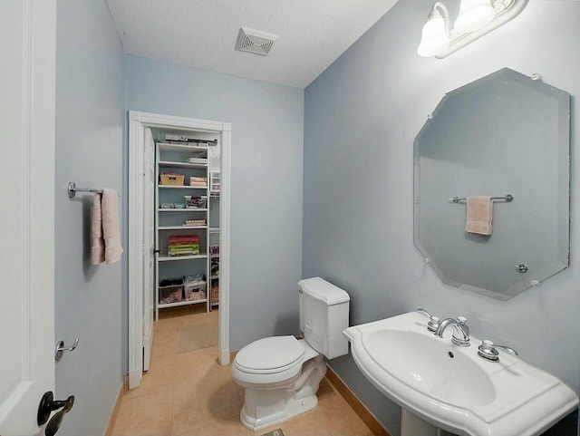 bathroom featuring toilet, tile patterned flooring, a textured ceiling, and sink