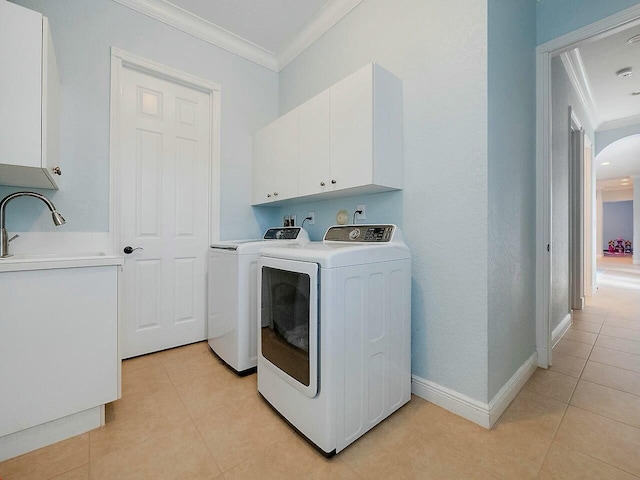 clothes washing area featuring sink, cabinets, light tile patterned flooring, ornamental molding, and washer and clothes dryer