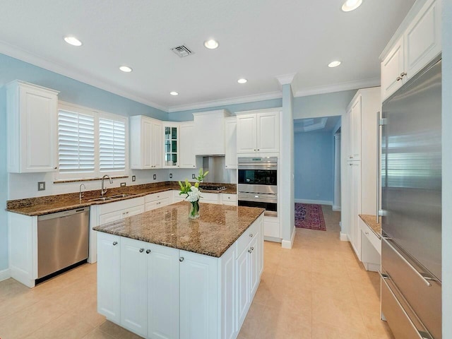 kitchen featuring stainless steel appliances, white cabinets, a kitchen island, and a sink