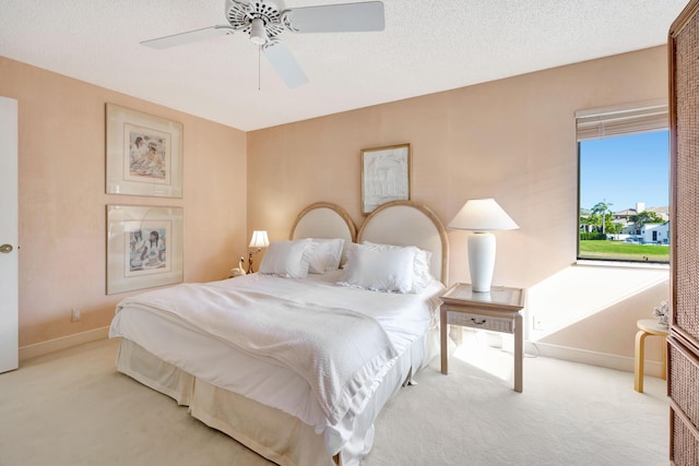 carpeted bedroom with ceiling fan and a textured ceiling