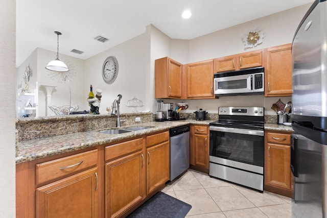 kitchen with light stone countertops, pendant lighting, stainless steel appliances, light tile patterned floors, and sink