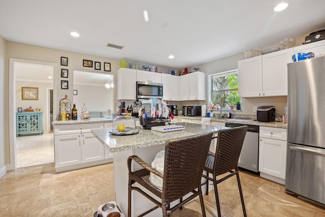 kitchen with stainless steel appliances, light stone countertops, and white cabinets