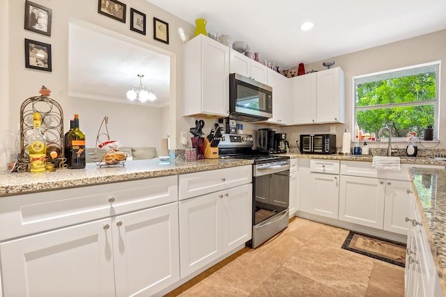 kitchen featuring light stone countertops, appliances with stainless steel finishes, white cabinets, and an inviting chandelier