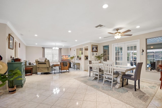 dining area featuring light tile patterned flooring, ornamental molding, ceiling fan with notable chandelier, and french doors