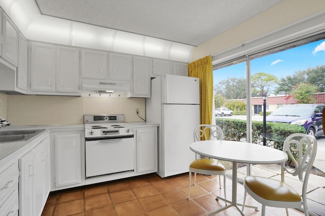 kitchen with white appliances, white cabinets, tile patterned floors, and sink