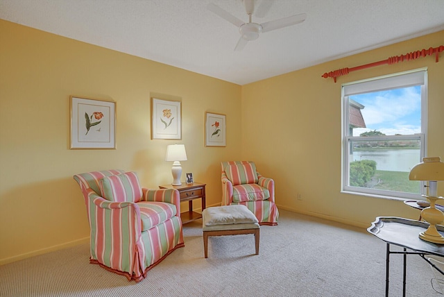 sitting room featuring carpet floors, ceiling fan, and a water view